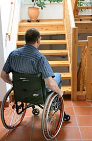 Foto: Ein Mann im Rollstuhl steht vor einer Treppe