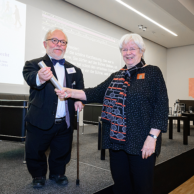 Ulrike Mascher übergibt symbolisch den DBR-Vorsitz an Volker Langguth-Wasem, indem sie ihm einen silbernen Staffelstab überreicht.