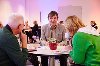 Austausch im Sitzen am Bistro-Tisch - Andreas Bethke (Mitte) im Gespräch mit Hans-Günter Heiden und Christiane Möller