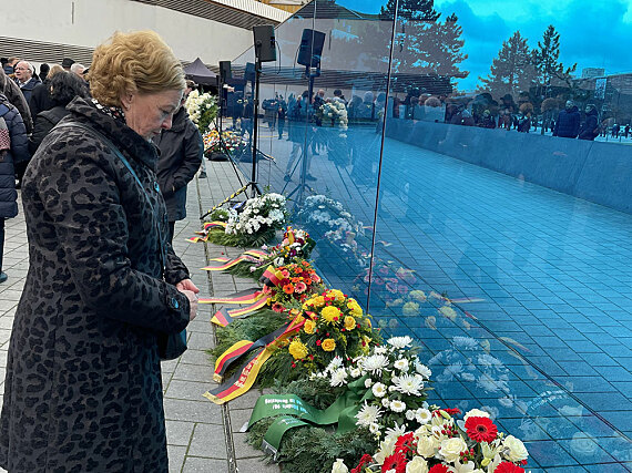 Michaela Engelmeier steht am T4-Denkmal in Berlin und blickt auf einige Blumenkränze nieder.